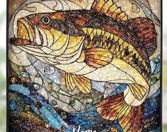 Könnte beinhalten: Glasfenster mit einem Schwarzbarsch in Braun-, Gelb- und Blautönen. Der Fisch wird in einer dynamischen Pose dargestellt, umgeben von stilisiertem Wasser und Blasen. Das Wort "Name" steht unten.