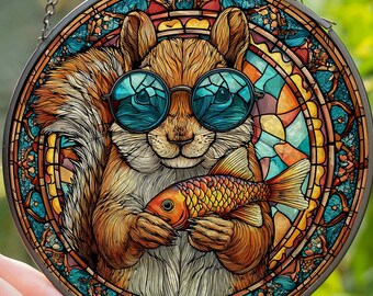Könnte beinhalten: Runde Glasfensterkunst mit einem Eichhörnchen, das eine Sonnenbrille trägt und einen Fisch hält. Das Eichhörnchen ist braun mit weißer Brust. Die Glasfensterkunst hat ein farbenfrohes Buntglasdesign mit dem Wort "NAME" am unteren Rand. Es hängt an einer silbernen Kette.