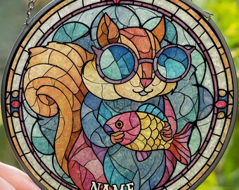 Könnte beinhalten: Runde Glasfensterkunst mit einem Eichhörnchen, das eine Sonnenbrille trägt und einen Fisch hält. Das Eichhörnchen ist in Braun-, Gelb- und Orangetönen gehalten, mit einem blauen und violetten Hintergrund. Der Fisch ist rosa und gelb. Das Wort "NAME" steht unten.