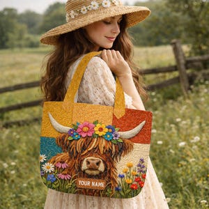 May include: A quilted tote bag featuring a brown Highland cow with a floral crown of daisies and colorful wildflowers. The background is divided into yellow, teal, and cream sections with a quilted texture. A rectangular tag displays the text YOUR NAME.