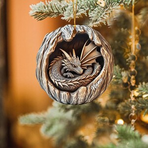 May include: A brown, wooden, tree-shaped Christmas ornament with a sleeping dragon inside. The ornament has the word "Name" inscribed on it.