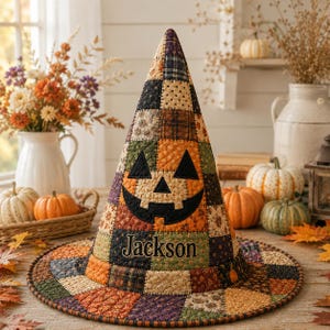 May include: A quilted witch hat featuring a patchwork design of autumn-colored fabrics in orange, brown, green, and purple. The hat displays a black fabric jack-o'-lantern face and the embroidered name Jackson in a dark script font.