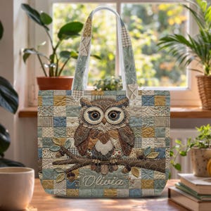 May include: A quilted tote bag featuring a patchwork pattern in shades of blue, tan, and cream. The center displays an embroidered owl perched on a branch with leaves and acorns. The name Olivia is embroidered in white script below the owl.