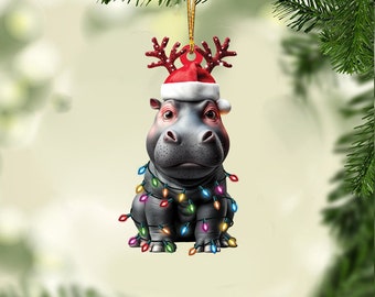 May include: A gray hippopotamus wearing a red Santa hat with reindeer antlers and wrapped in colorful Christmas lights. The hippopotamus is a Christmas ornament.