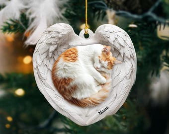 Könnte beinhalten: Weißer Keramik-Herzen-Anhänger mit einer schlafenden orange-weißen Katze im Inneren. Das Herz hat Flügel und der Text "Name" ist unten aufgedruckt.