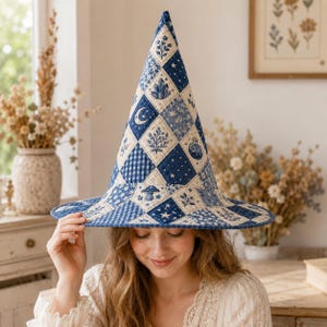 May include: A tall, pointed hat featuring a blue and white quilted patchwork design. The fabric squares display various patterns including stars, crescent moons, crystals, mushrooms, potion bottles, and floral motifs in shades of navy and cream.