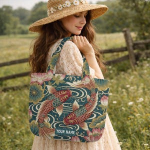 May include: A rectangular tote bag featuring a dark teal background with a pattern of two red koi fish, lotus flowers, and swirling water lines. A rectangular patch at the bottom center displays the white text YOUR NAME on a teal background.