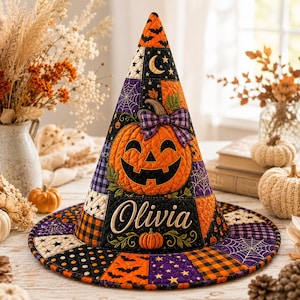 May include: A quilted witch hat featuring a patchwork design of orange, black, and purple fabrics with patterns of pumpkins, spiderwebs, stars, and bats. The hat displays a large central jack-o'-lantern and the embroidered name Olivia.