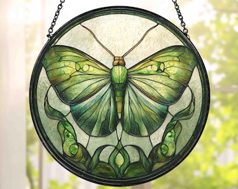 May include: Round stained glass window art featuring a green butterfly design. The butterfly has detailed wings and body, with a dark border and hanging chain. The glass has a textured appearance, and the colors include shades of green and brown.