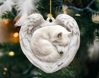 Könnte beinhalten: Weißer Keramik-Anhänger mit einem schlafenden Wolf in einem herzförmigen Rahmen mit Engelsflügeln. Der Anhänger hat den Schriftzug "Name" unten.