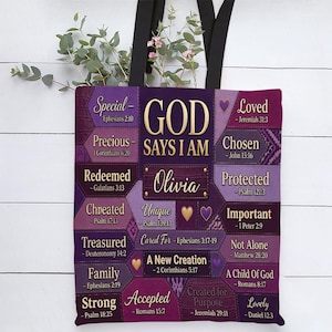 May include: A purple tote bag with black straps featuring a patchwork design of various shades of purple. The text reads GOD SAYS I AM, Olivia, and includes inspirational words like Special, Loved, Precious, Chosen, Redeemed, and Protected.