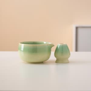 Pu&ograve; includere: Una tazza da t&egrave; in ceramica verde e bianca e una teiera abbinata con un beccuccio.