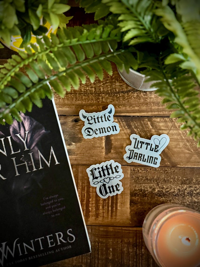 May include: Three white stickers with black gothic lettering. The stickers say "Little Demon", "Little Darling", and "Little One" with a heart and chain design.