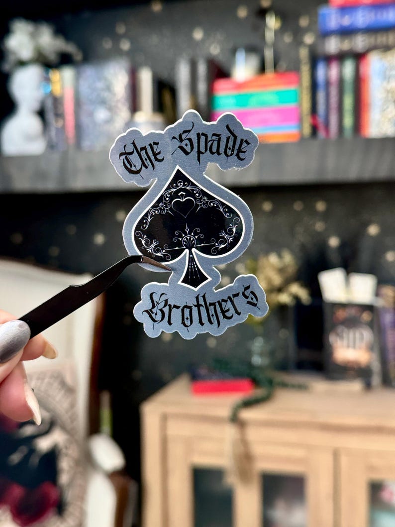 May include: A silver sticker with a black spade design and the text "The Spade Brothers".