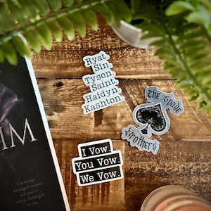 May include: Three black and white stickers with text. The first sticker has the text "I Vow. You Vow. We Vow." The second sticker has the text "The Spade Brothers." The third sticker has a list of names: "Ryat. Sin. Tyson. Saint. Haidyn. Kashton."