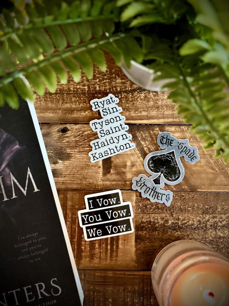 May include: Three black and white stickers with text. The first sticker has the text "I Vow. You Vow. We Vow." The second sticker has the text "The Spade Brothers." The third sticker has a list of names: "Ryat. Sin. Tyson. Saint. Haidyn. Kashton."