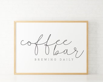 May include: A framed print with the text "coffee bar brewing daily" in a cursive font. The frame is light wood.