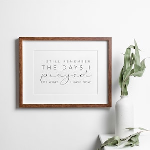 May include: A framed print with a white background and black text that reads "I still remember the days I prayed for what I have now". The frame is brown wood.