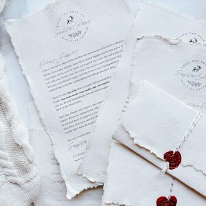 May include: Off-white, textured paper letters and envelopes with torn edges. The letters feature the text "From the Desk of Santa Claus" and handwritten messages. Red wax seals secure the envelopes, tied with white string.