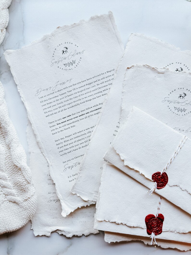 May include: Off-white, textured paper letters and envelopes with torn edges. The letters feature the text "From the Desk of Santa Claus" and handwritten messages. Red wax seals secure the envelopes, tied with white string.