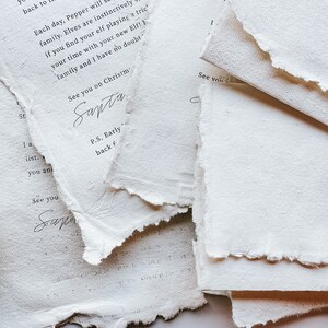 May include: Close-up of torn, textured white paper with handwritten text. The text includes phrases like "See you on Christmas" and "Santa". The paper has a rustic, handmade appearance, suggesting a vintage or artisanal theme.