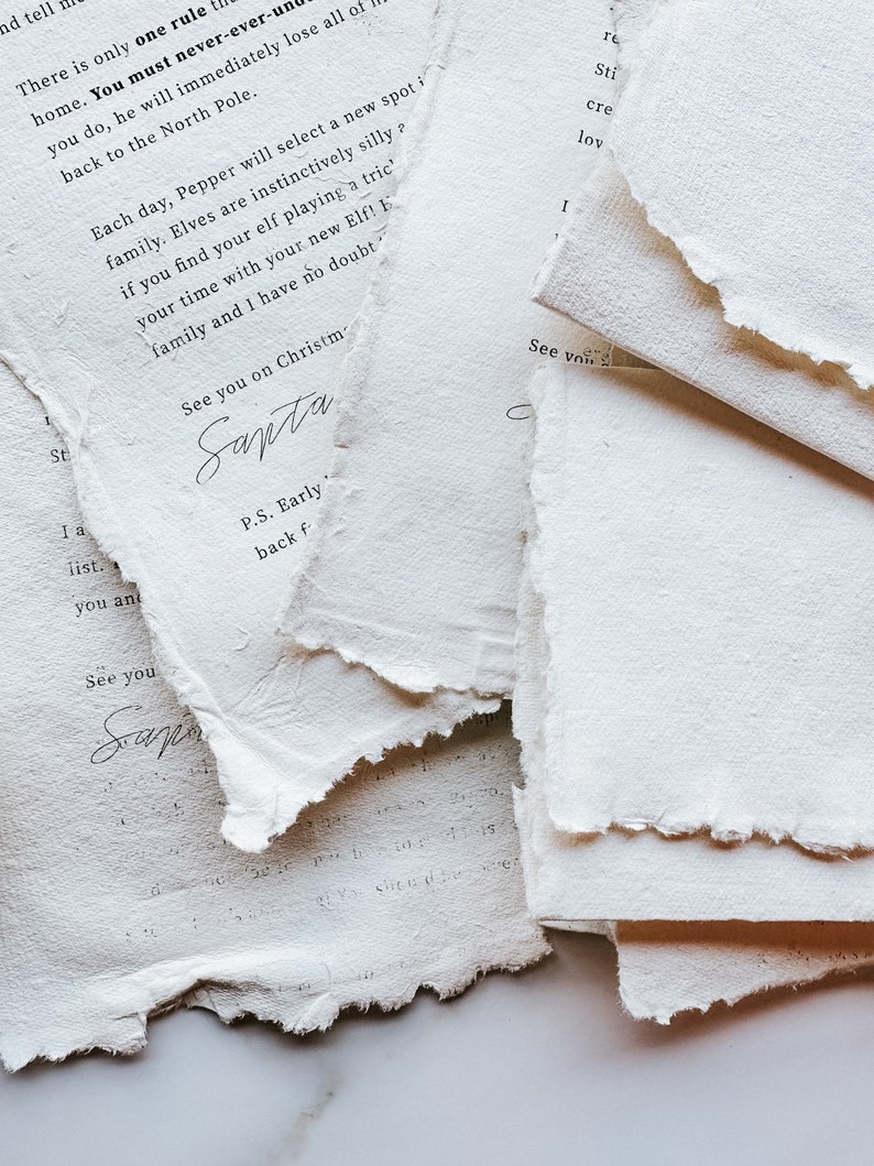 May include: Close-up of torn, textured white paper with handwritten text. The text includes phrases like "See you on Christmas" and "Santa". The paper has a rustic, handmade appearance, suggesting a vintage or artisanal theme.