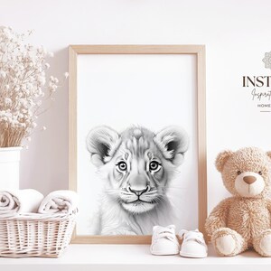 May include: Black and white illustration of a lion cub's face. The image is framed and displayed on a shelf with a teddy bear and other decor.
