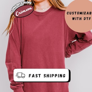 May include: Crimson long-sleeve shirt with the text "Comfort Colors" and "Customizable with DTF". The shirt also has the text "Fast Shipping" on it.