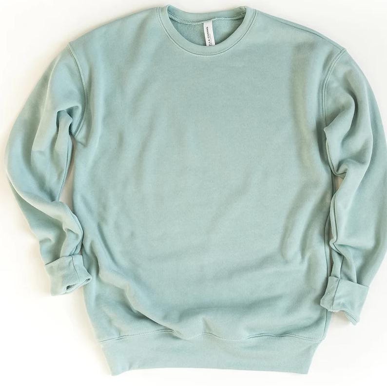 May include: A solid, light teal crewneck sweatshirt. The long sleeves have folded cuffs, and the neckline is a simple, round design. The sweatshirt is made of a soft material and is a solid color.