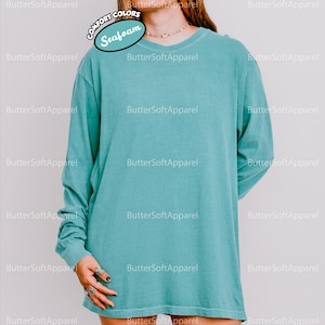 May include: A long-sleeved, seafoam green shirt with a crew neck. The shirt is made of a soft material. The text "COMFORT COLORS" and "Seafoam" are visible on the image. The brand name "ButterSoftApparel" is also visible.