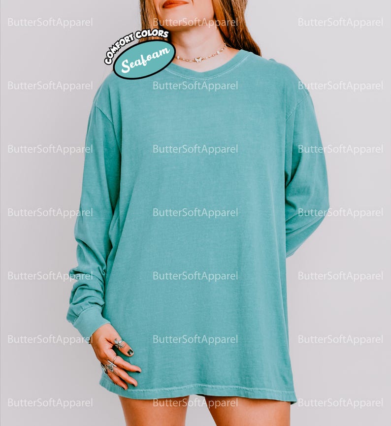 May include: A long-sleeved, seafoam green shirt with a crew neck. The shirt is made of a soft material. The text "COMFORT COLORS" and "Seafoam" are visible on the image. The brand name "ButterSoftApparel" is also visible.