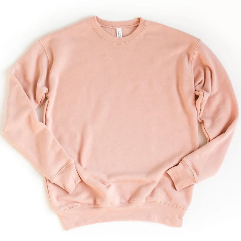 May include: A solid-colored, long-sleeved sweatshirt in a soft, muted pink hue. The crew neck sweatshirt has ribbed cuffs and hem. The fabric appears to be a soft, comfortable material. A simple, casual top for everyday wear.