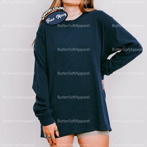 May include: A navy blue long-sleeved shirt. The shirt features the text "COMFORT COLORS True Navy" on the upper left. The shirt is made of a soft material. The brand name "ButterSoftApparel" is printed repeatedly on the background.