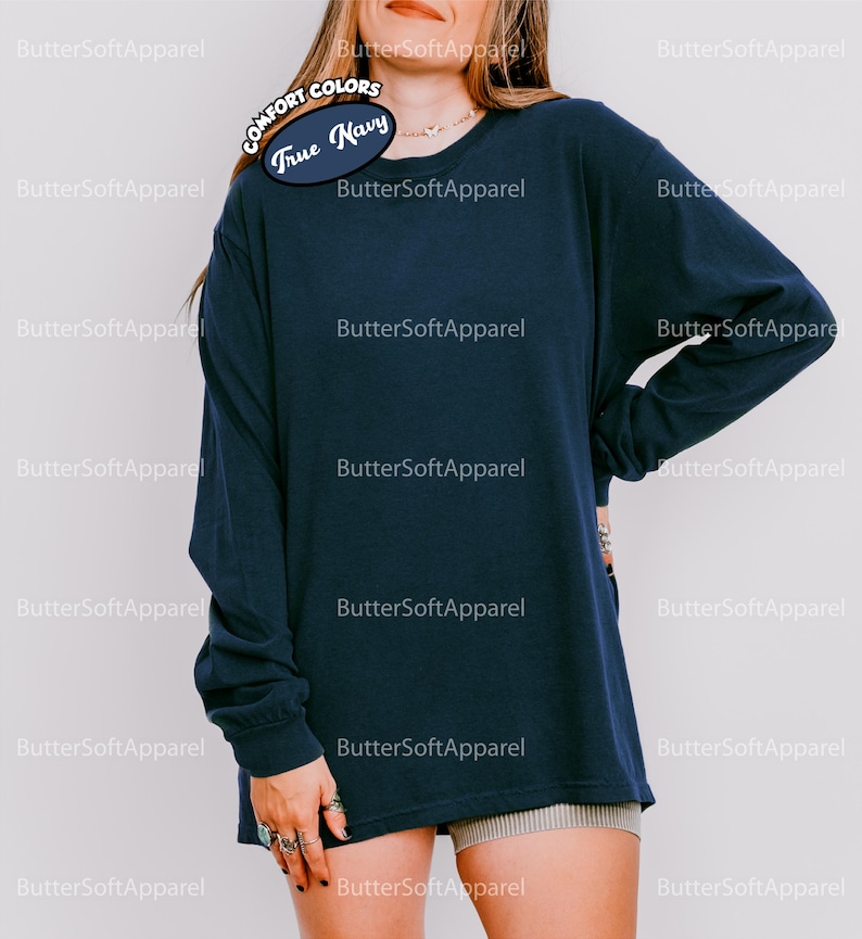 May include: A navy blue long-sleeved shirt. The shirt features the text "COMFORT COLORS True Navy" on the upper left. The shirt is made of a soft material. The brand name "ButterSoftApparel" is printed repeatedly on the background.
