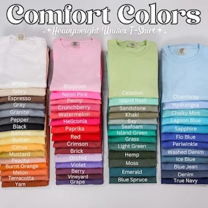 May include: A display of folded Comfort Colors unisex t-shirts in a range of colours, such as pink, green, and blue. The image shows a colour chart with names like "Blossom," "Celedon," and "Chambray."