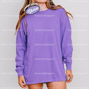 May include: A long-sleeved violet shirt. The shirt has a crew neck and is a solid colour. The image includes the text "COMFORT COLORS" and "Violet". The brand name "ButterSoftApparel" is also visible.