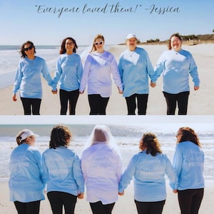 May include: A group of people on a beach wearing light blue long-sleeved shirts and black trousers, holding hands. The shirts have the text "Happily Ever After Protector" on the back. The image includes the quote "Everyone loved them!" - Jessica.