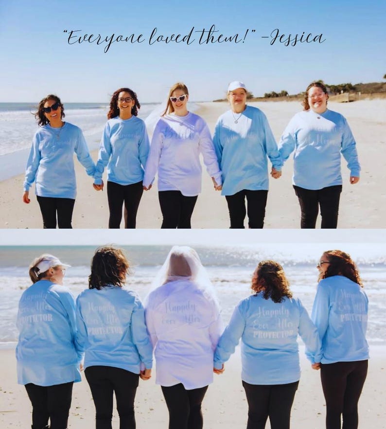 May include: A group of people on a beach wearing light blue long-sleeved shirts and black trousers, holding hands. The shirts have the text "Happily Ever After Protector" on the back. The image includes the quote "Everyone loved them!" - Jessica.