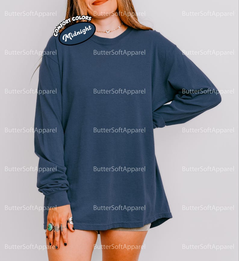 May include: A navy blue long-sleeved shirt with a crew neck and a relaxed fit. The text "Midnight" is displayed on a circular label. The shirt is made of a soft, comfortable material. Part of the Comfort Colors collection.