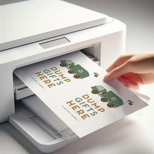 Pode incluir: Uma impressora branca imprimindo duas folhas de papel com o texto "DUMP GIFTS HERE" em marrom e verde. Cada folha apresenta um caminhão de lixo verde de desenho animado com um símbolo de reciclagem. Uma mão puxa uma folha impressa.