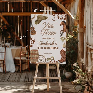 Op de afbeelding: Een bord van 61 cm bij 46 cm op een ezel met een western thema. Op het bord staat "Yee Haw" en "Welkom bij Chadrick's 2e verjaardag". Het bevat illustraties van een cowboyhoed, gitaar, paard en laarzen.