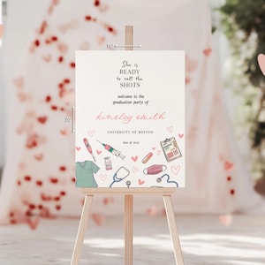 May include: A graduation party welcome sign on a wooden easel. The sign has text that reads "She is READY to call the SHOTS" and welcomes guests to Kinsley Smith's graduation party. The sign includes medical-themed illustrations and hearts.