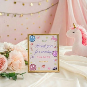 May include: A gold-framed sign with the text Thank you for coming, PLEASE TAKE ONE, and 07.23.20XX. The sign features colorful illustrations of smiley faces, a unicorn, a rainbow, a crown, a strawberry, and shoes on a light background.