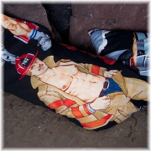 May include: Black fabric with a repeating pattern of illustrations of a shirtless firefighter in a red hat and tan coat. Other illustrations include a person's legs and a building.