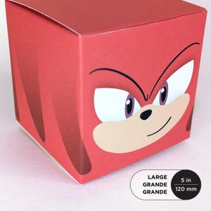 May include: A red, cube-shaped box featuring a cartoon character's face. The character has white eyes with purple irises, a tan muzzle, and a black nose and mouth. The box is labeled "LARGE" and measures 5 inches (120 mm).