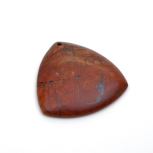 May include: A triangular pendant made of red jasper with brown and black veins. The pendant has a hole at the top for stringing.