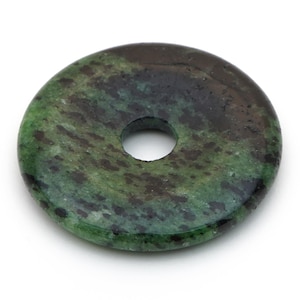 May include: A round, polished stone with a central hole. The stone features a mottled pattern of dark green and black hues. The surface is smooth and reflective, suggesting a natural gemstone or mineral.