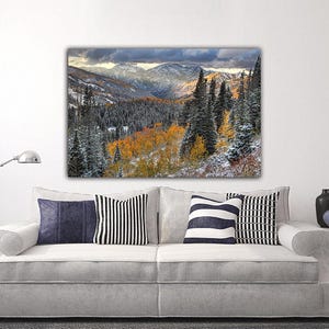 a large landscape painting hanging on a wall above a white sofa with striped pillows.