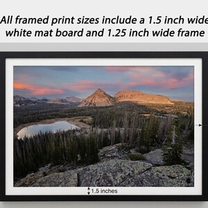 The image is a framed print depicting a scenic mountain landscape with a lake and pine trees.