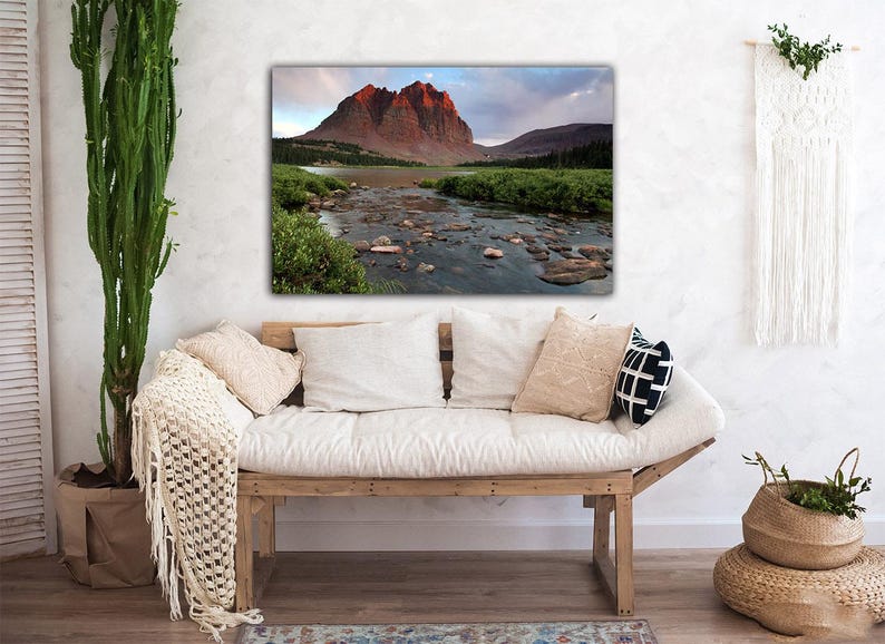 a cozy living room with a large framed landscape photograph hanging on the wall, depicting a mountain river flowing through a lush green valley.